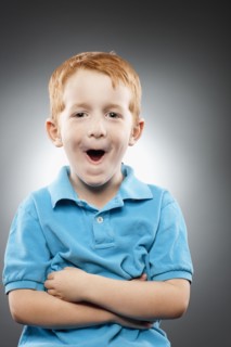 Portrait of smiling redhead boy (4-5) wearing blue polo shirt and making face, studio shot. Photo :