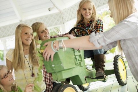 USA, Utah, family portrait of sisters (6-7, 8-9, 12-13, 14-15, 16-17) at table playing with tractor