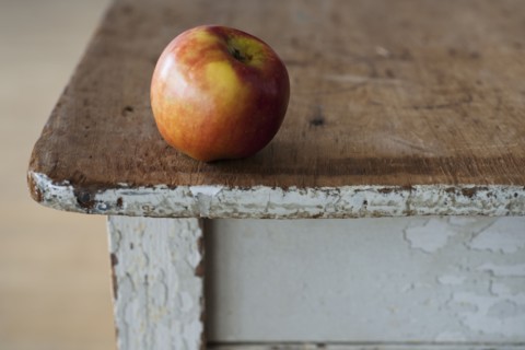 Apple on the egde of table.