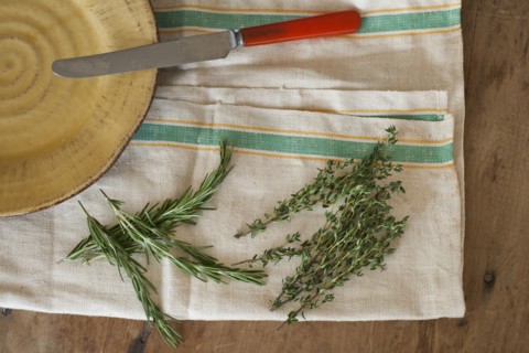 Rosemary and thyme with kitchen knife lying on kitchen cloth, directly above.
