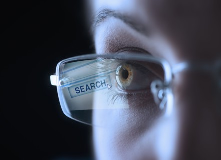 Reflection of search button in businesswoman's glasses.