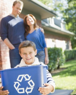 USA, New York, Flanders, Boy (8-9) holding bucket with recycling symbol, parents in background.