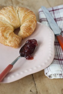 Croissant with jam on plate.