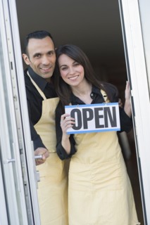 Couple holding open sign.