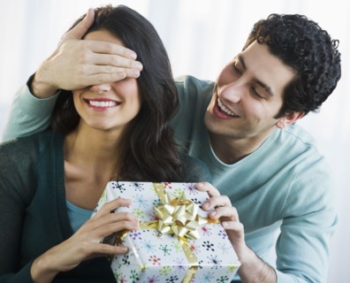 Young man giving his girlfriend present while covering her eyes. Photo : Daniel Grill