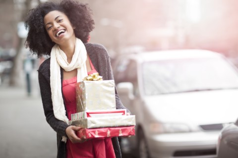 USA, Washington State, Seattle, Young cheerful woman carrying stack of boxed gifts. Photo : Take A