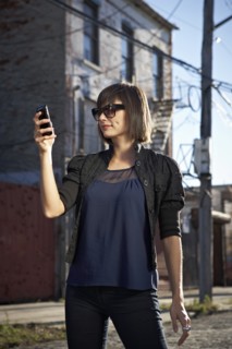 USA, New York City, Brooklyn, woman in street using phone. Photo : Shawn O'Connor