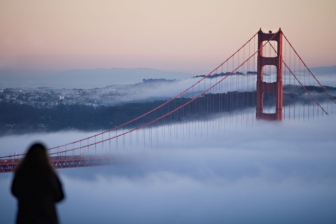 USA, California, San Francisco, Woman watching Golden gate Bridge in fog. Photo : Noah Clayton
