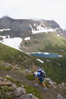 USA, Montana, Glacier National Park, Mid adult woman hiking with backpack during rain. Photo : Noah