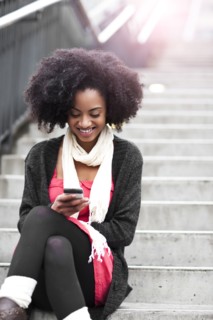 USA, Washington State, Seattle, young woman sitting on steps and text messaging. Photo : Take A Pix