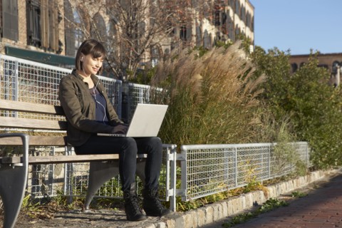 USA, New York City, Brooklyn, woman on bench using laptop. Photo : Shawn O'Connor