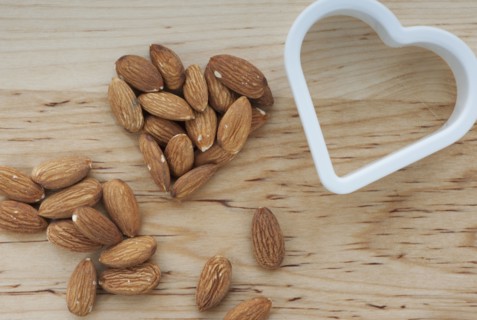 Heart shaped almonds with cutter on chopping board.