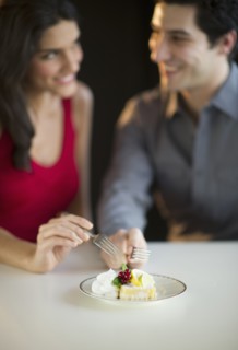 Young happy couple sharing dessert, studio shot.