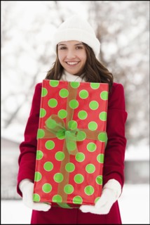 USA, Utah, Lehi, Portrait of young woman holding Christmas gift outdoors. Photo : Mike Kemp