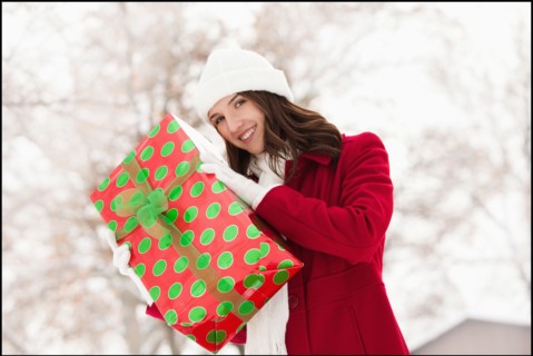 USA, Utah, Lehi, Portrait of young woman holding Christmas gift outdoors. Photo : Mike Kemp