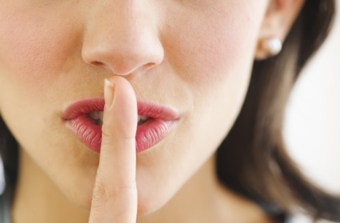 Young woman with finger on lips, close-up.
