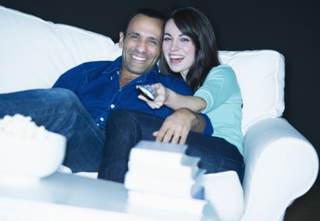 Couple watching television on sofa.