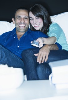 Couple watching television on sofa.