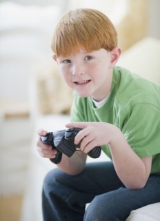 Portrait of boy (8-9) playing video game. Photo : Jamie Grill Photography