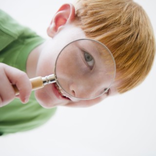 Portrait of boy (8-9) looking through magnifying glass. Photo : Jamie Grill Photography