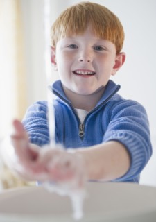 Portrait of boy (8-9) washing hands. Photo : Jamie Grill Photography
