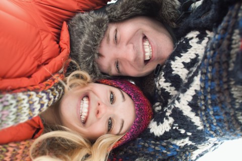 Portrait of young couple lying in snow. Photo : Mike Kemp