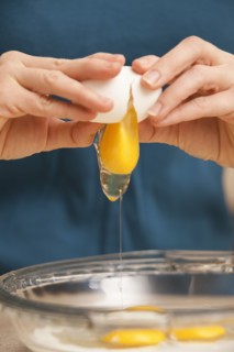 Womans hands cracking eggs. Photo : Mike Kemp