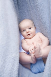 Portrait of baby boy (6-11 months) in bedclothes. Photo : Noah Clayton