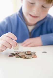 Portrait of boy (8-9) counting coins. Photo : Jamie Grill Photography