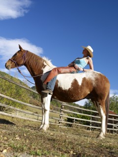 USA, Colorado, Cowgirl relaxing with horse on ranch. Photo : John Kelly
