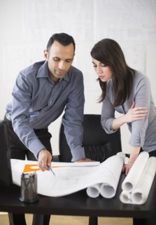Business man and woman studying blueprints.