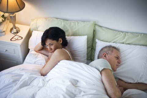 Mature couple laying in bed after argument.