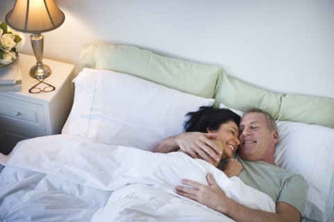 Happy mature couple laying in bed.