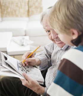 Grandfather and grandson (8-9) doing crossword. Photo : Jamie Grill Photography
