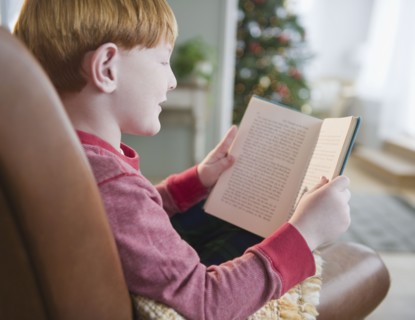 Boy (8-9) reading book on Christmas Eve. Photo : Jamie Grill Photography
