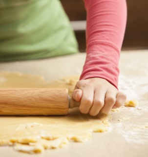 Close-up of girl (6-7) rolling dough. Photo : Mike Kemp