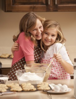Portrait of two girls (10-11) baking in kitchen. Photo : Mike Kemp