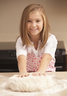 Portrait of girl (10-11) kneading dough in kitchen. Photo : Mike Kemp