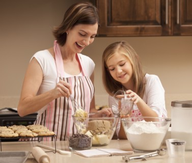 Mother baking with daughter (10-11) in kitchen. Photo : Mike Kemp