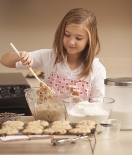 Girl (10-11) baking biscuits in kitchen. Photo : Mike Kemp