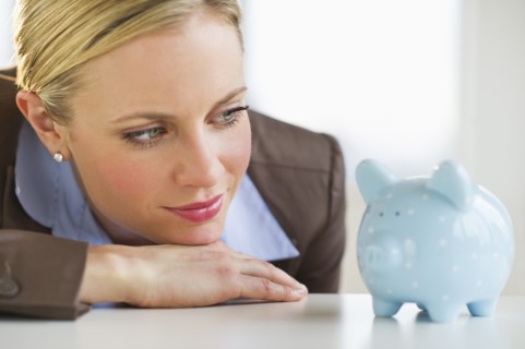 Businesswoman looking at piggy bank. Photo : Daniel Grill