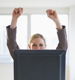 Businesswoman peeking from behind computer. Photo : Daniel Grill