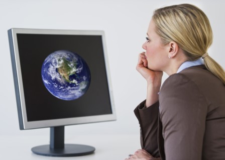 Businesswoman looking at monitor with globe. Photo : Daniel Grill