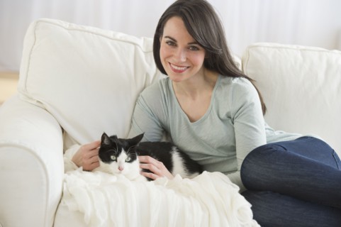 Portrait of woman with cat on sofa.