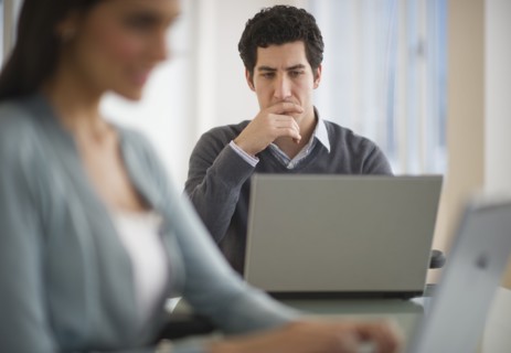Business man and woman using laptops in office.