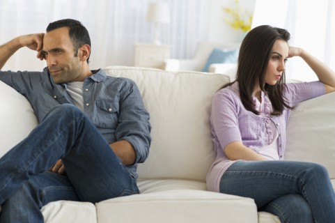 Couple sitting on sofa back to back.
