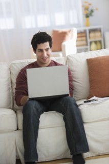 Man using laptop on sofa.