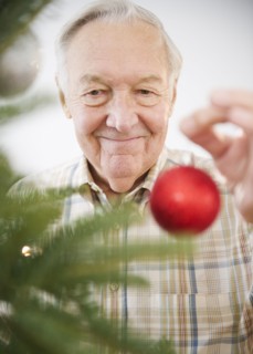 Portrait of senior man decorating Christmas tree. Photo : Jamie Grill Photography