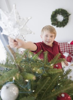 Boy (8-9) decorating Christmas tree. Photo : Jamie Grill Photography