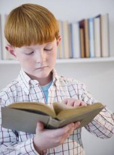 Boy (8-9) reading book. Photo : Jamie Grill Photography